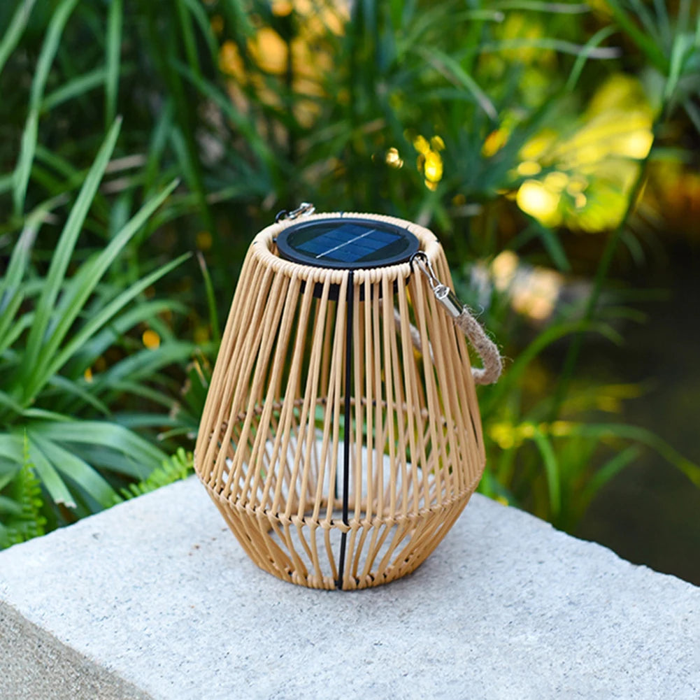 Woven solar rattan lantern on a stone surface with greenery in the background