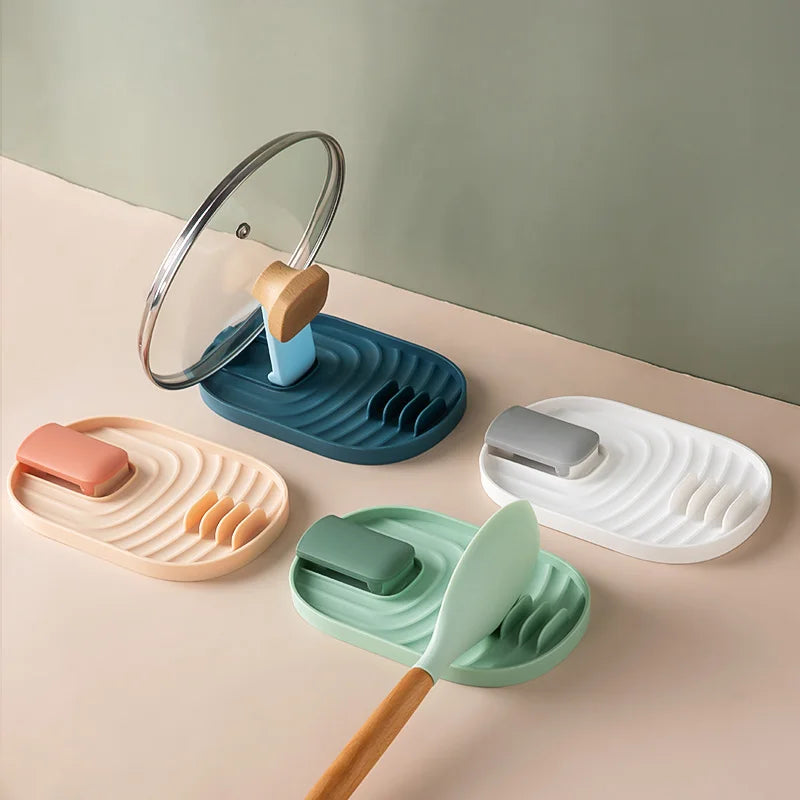 Colorful silicone spatula and lid holders with multi-slot design, shown holding cooking utensils and a pot lid on a kitchen surface