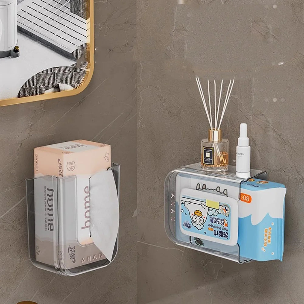 Wall-mounted transparent wipe holders in bathroom, one holding tissue pack and the other used as a shelf for toiletries and diffuser