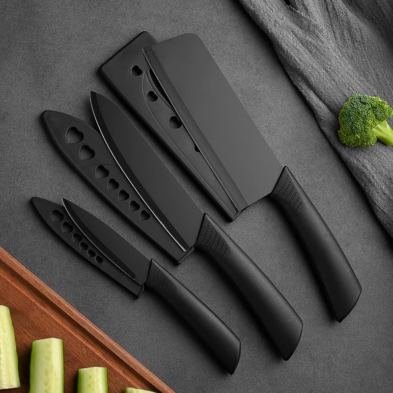 Set of black kitchen knives on a gray surface with vegetables.