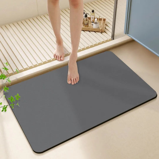 Person stepping onto a gray bath mat in a bathroom setting.