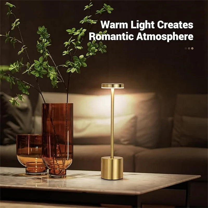 Gold table lamp on a marble surface with decorative glasses and a vase, text 'Warm Light Creates Romantic Atmosphere' above.