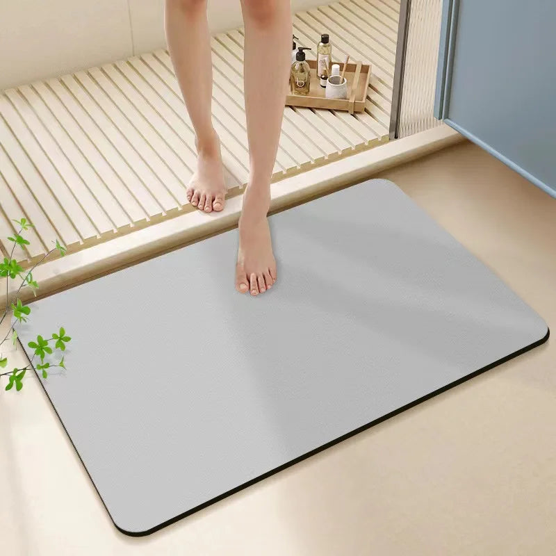 Person stepping onto a large gray bath mat in a bathroom setting.