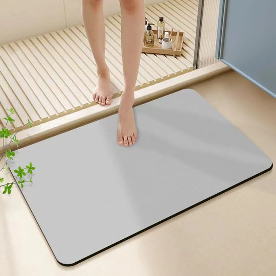 Person stepping onto a large gray bath mat in a bathroom setting.