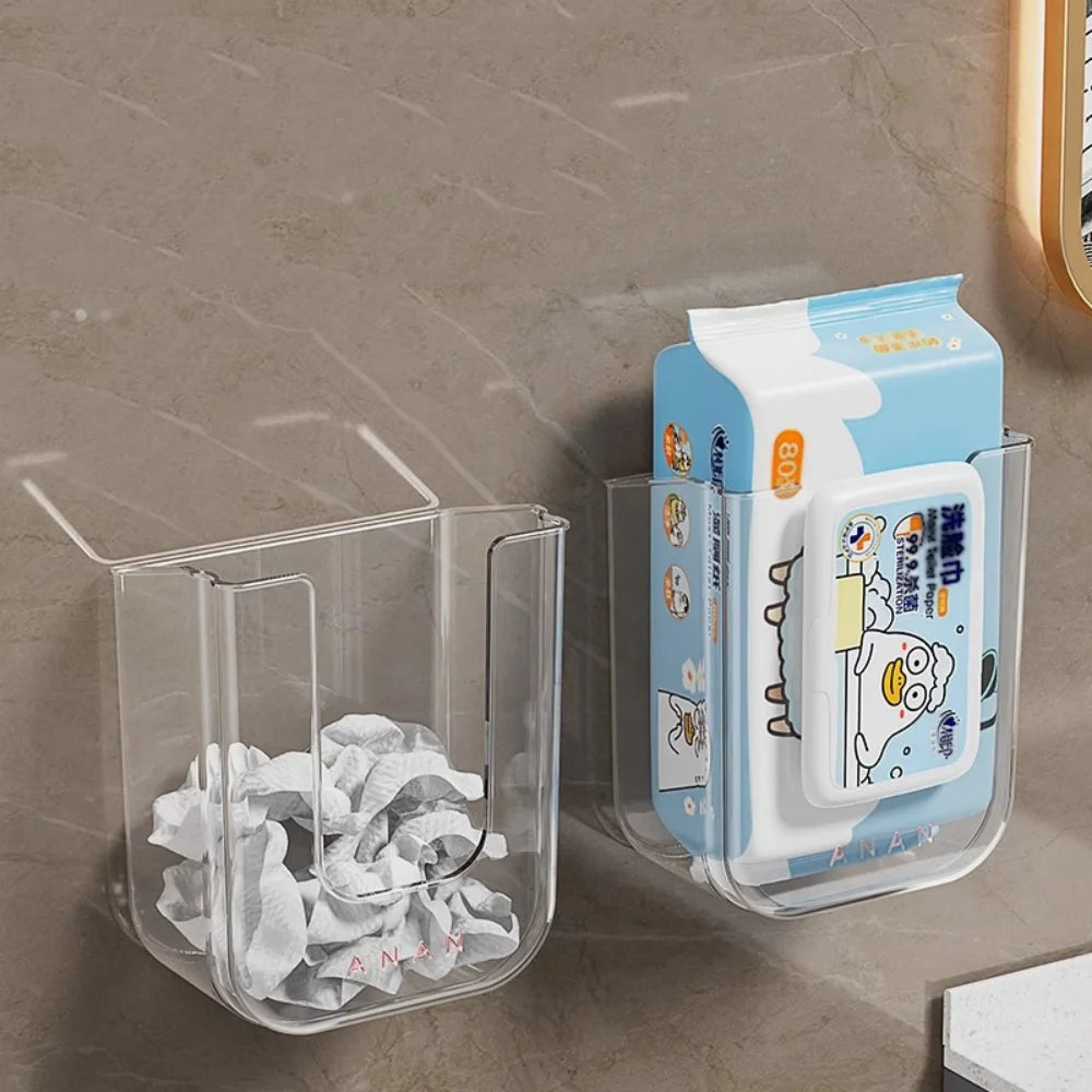Clear wall-mounted holder with tissues and a box of wipes on a gray tiled wall.