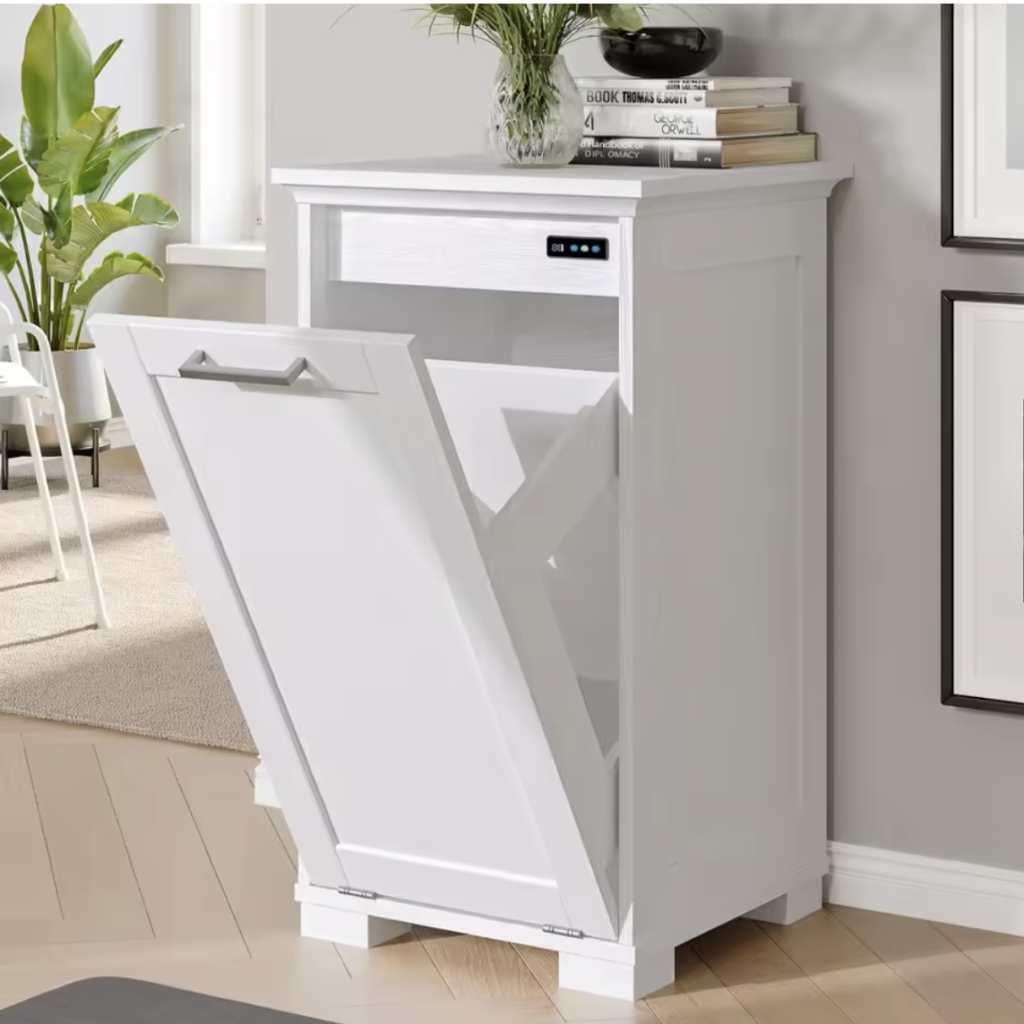 White tilt out trash bin with a lid in a room with a desk and plants.