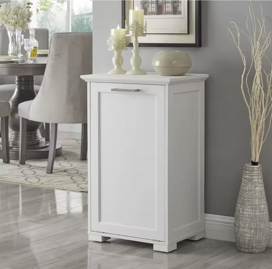 White tilt out trash can cabinet in a dining room setting with decor items on top