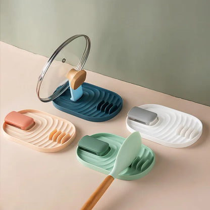 Colorful silicone spatula and lid holders with multi-slot design, shown holding cooking utensils and a pot lid on a kitchen surface